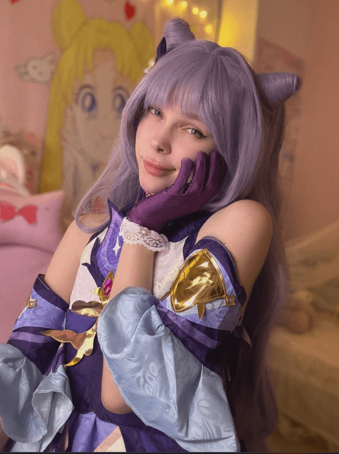 Cosplayer in a purple lavender outfit with cat-ear headband and gloves, resting her face on her gloved hand in a pastel bedroom setting.